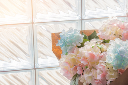Flowers plastic bouquet on brick glass wall background.の写真素材
