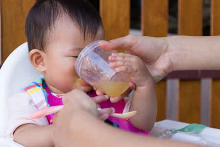 Asian cute baby eating food, Mother feeding soup water for young kid eight month at home.の写真素材