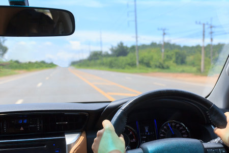 View inside a car on road background, hands driving in highway.