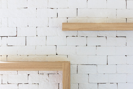 Brown wood frame on white brick background. Vintage furniture wooden frame hanging on white brick wall texture.の写真素材