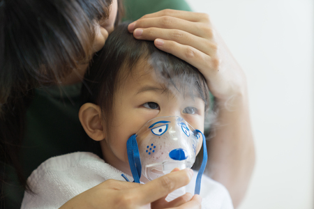 Asian baby girl breathing treatment with mother take care, at room hospital, close up health care kid concept sunny light background.の写真素材