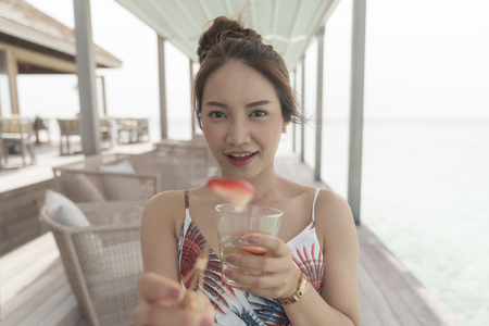 Asian beautiful woman enjoyful drink cocktail in resort island, vacation holiday concepts with tropical Maldives island background.の写真素材