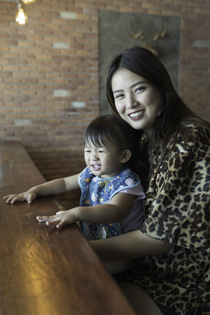 Asian family happiness, with baby girl and parent in the cafe.の写真素材