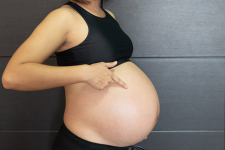 Pregnant asian woman touching her big belly happily, Close up.