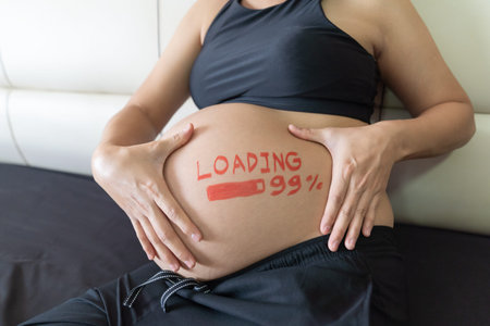 Close up. pregnant woman touching on her big belly, with loading 99% concept painted on belly.