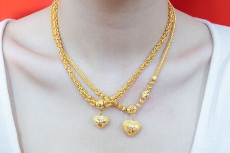 Close up. Beautiful neck girl with gold necklace. Woman in a golden heart necklace jewelery. Beauty and accessories.の写真素材
