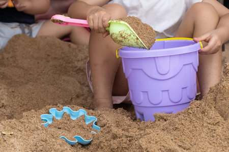 Children 's hands are touching plastic toys in sand on the beach, sand play activities.