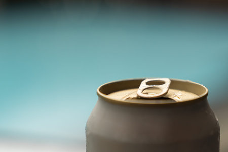 Close up. Opened beer can on swimming pool background.