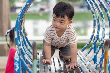 Asian little baby boy enjoy with outdoor zone kid park, climbing steel toy activity on the playground.の写真素材