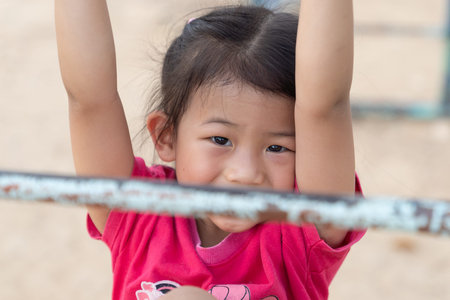 Asian little baby girl enjoy with outdoor zone kid park, climbing steel toy activity on the...
