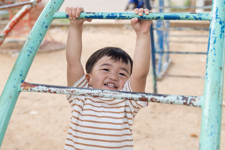 Asian little baby boy enjoy with outdoor zone kid park, climbing steel toy activity on the...