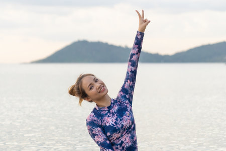 Asian swimwear woman with slim body swimming in sunset sea banner of water copyspace. Travel holiday girl relaxing on beach vacation.の写真素材
