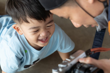 Asian dad is enjoying son taking a photo.の写真素材