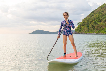 Stand up paddle board woman paddleboarding on beach, Thailand. standing happy on paddleboard on blue...