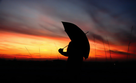Silhouette of woman with umbrella on yellow backgroundの写真素材