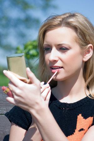 The attractive girl paints lips with lipstickの写真素材