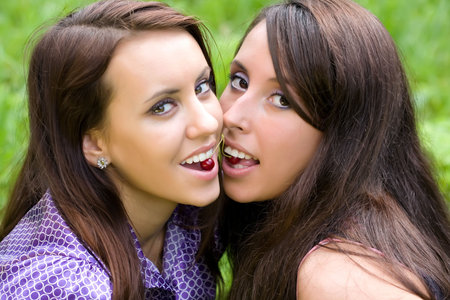 Girlfriends playing a brush of berries of a cherry