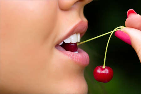 Sensual lips of the girl tasting a cherryの写真素材