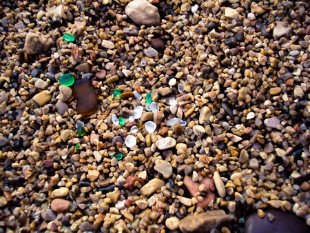 Multi-colored sea pebbles with glass pieces on the beachの写真素材