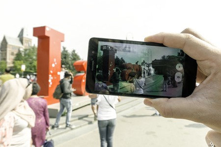 Young woman tourist photographing an art object IAmsterdam. Amsterdam Netherlands September 2017.のeditorial素材