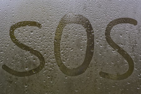 inscription on the sweaty glass with the finger is a sos.の写真素材