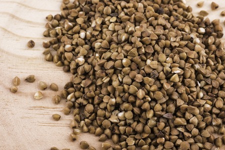 wooden bowl of buckwheat grains on a wooden table.の写真素材