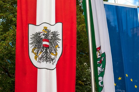Austrian flag with coat of arms develops in the wind.の写真素材