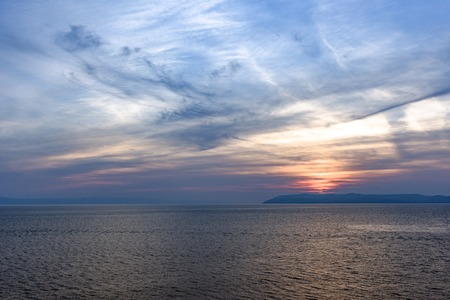 Sunset over the sea with mysterious sky with reflection in the waterの写真素材