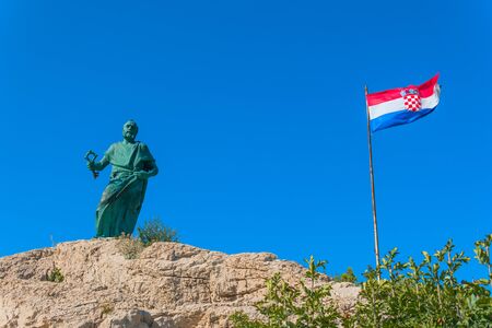 Makarska September 2018 Croatia. Monument to St. Peter and flag of Croatia sea entrance to the Harborのeditorial素材