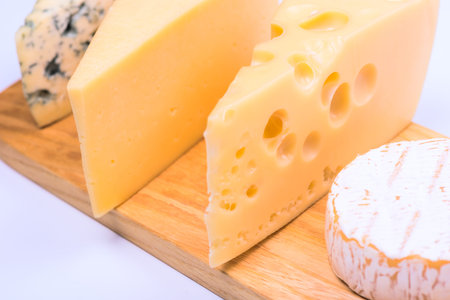 Delicious pieces of different cheese on a white table