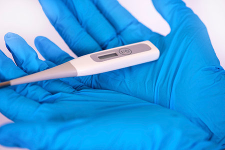 gloved hands hold a thermometer. coronavirus pandemicの写真素材