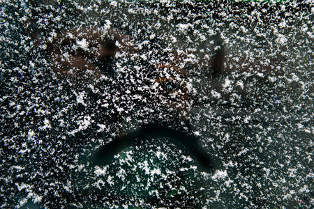sad face painted on the snow-covered car window