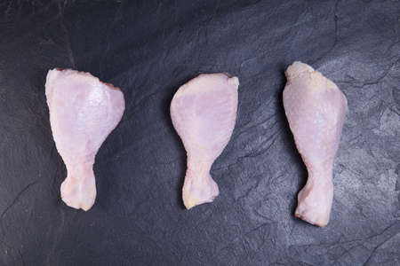 fresh chicken legs on a dark background close-upの写真素材