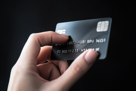 Close up view of female hand holding a credit card on black background. Generative AI.の素材