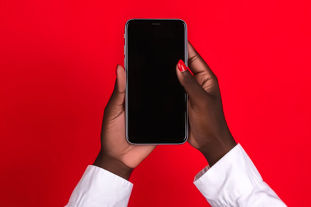 Cropped image of african american woman holding smartphone with blank screen on red background. Generative AI.の素材