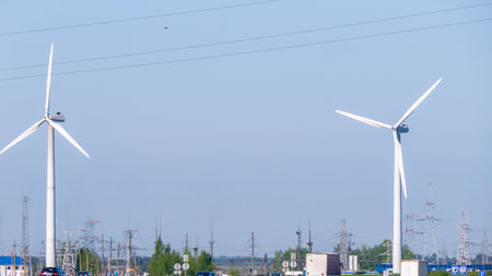 A wind turbine is standing tall in a field. The sky is clear and blue, and the wind turbine is the only object in the sceneの写真素材
