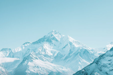 A snow-covered mountain with a clear blue sky in the background. The mountain is covered in snow, and the sky is a bright blue color. Concept of tranquility and peacefulnessの素材
