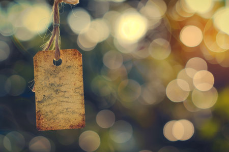 A rustic tag is suspended from a string, surrounded by a soft-focus background of blurred greenery and warm light, evoking a sense of calm and simplicity in nature.の素材