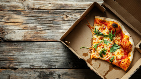 A flavorful slice of cheese pizza with melted cheese and fresh greens sits in an open takeout box, resting on a rustic wooden table. The time appears casual and inviting.の素材