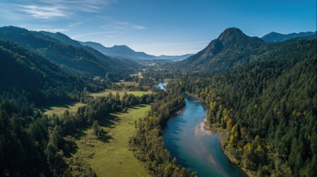 Lush valleys surround a shimmering river framed by towering mountains and vibrant trees on a sunny day.の素材