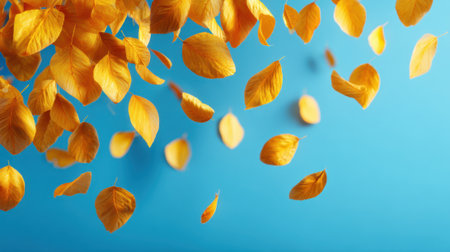 Bright yellow leaves fall gently in the air, creating a lively atmosphere set against a calming blue backdrop. This autumn moment captures nature's beauty and tranquility.の素材