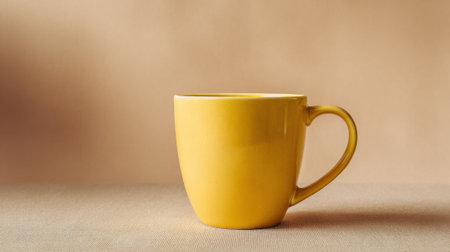 A cheerful yellow mug rests on a smooth brown table creating a cozy and inviting atmosphere.の素材