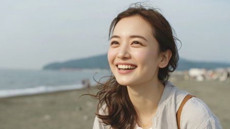 A young woman smiles happily while sitting on the sandy beach. The sun shines brightly above her, creating a joyful and peaceful atmosphere. Waves crash gently in the distance.の素材
