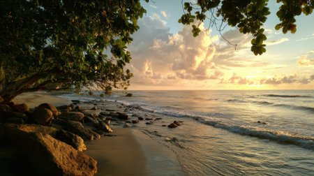 Golden hour casts a warm glow over a serene beach where gentle waves lap against a rocky shoreline. Lush trees frame the scene as clouds drift in the sky.の素材