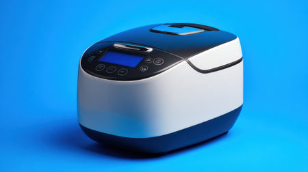 A contemporary rice cooker sits on a bright blue background showing its sleek design and user friendly interface.の素材