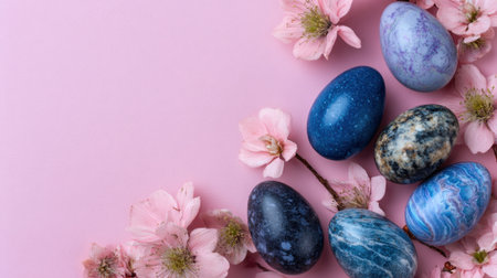 Colorful decorative eggs rest among soft pink blossoms on a light background.の素材