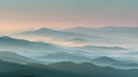 Early morning mist blankets the rolling hills revealing layers of mountains in pastel colors.の素材