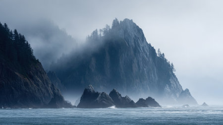 Fog blankets the coastline as towering cliffs rise above the ocean waves creating a serene scene.の素材