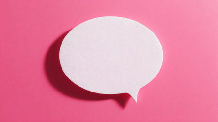 A blank speech bubble lies on a bright pink surface inviting thoughts and messages.の素材