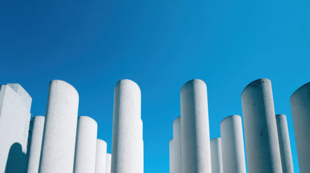Tall white pillars towards reach the bright blue sky creating a striking architectural scene.の素材